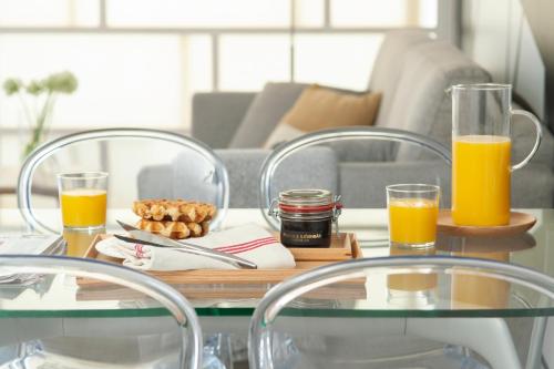 a table with two chairs and two glasses of orange juice at Eric Vökel Boutique Apartments - Hamburg Suites in Hamburg
