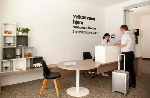 a man standing in front of a table with a laptop at Eric Vökel Boutique Apartments - Hamburg Suites in Hamburg