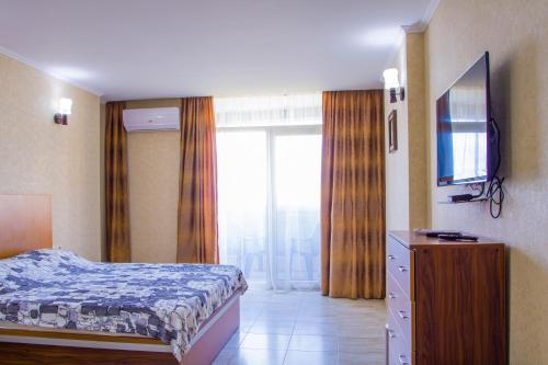 pokój hotelowy z łóżkiem i telewizorem w obiekcie Apartment ZARINA in apart-otel RESIDENC w mieście Batumi