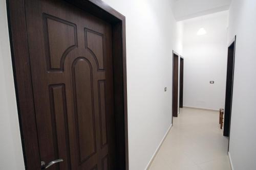 a hallway with a brown door and white walls at Hotel Agreno in Berat