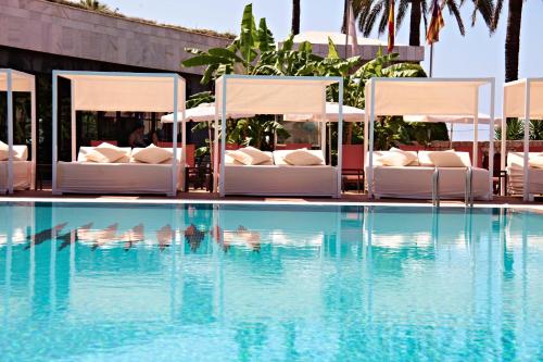 a hotel pool with beds and a swimming pool at Hotel Serrano Palace in Cala Ratjada