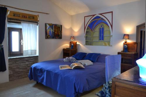 - une chambre avec un lit bleu et un livre dans l'établissement ValdericArte, à Lamoli Di Borgo Pace