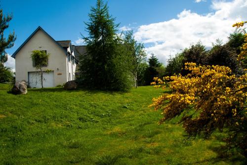 a white house in a field of green grass at Suardal Guest House in Fort Augustus