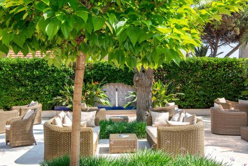 a patio with wicker chairs and a tree at Best Western Premier Montfleuri in Sainte-Maxime