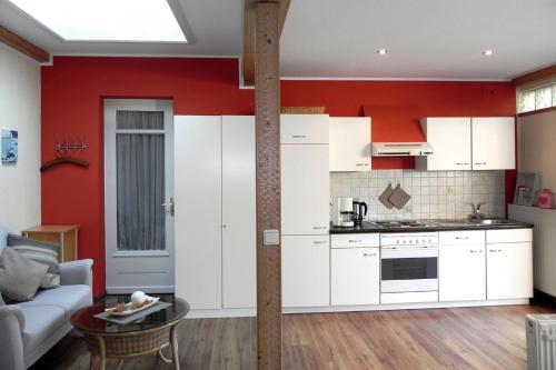 a kitchen with white cabinets and a red wall at Ferienwohnung Tilli in Zell an der Mosel