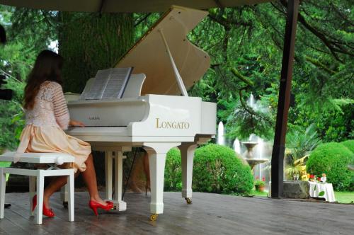 a woman is sitting at a white piano at Hotel Villa Luppis in Pasiano di Pordenone