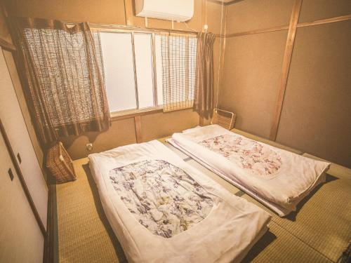 a room with two beds in it with a window at Nostalgic guesthouse for 1 to 2 Females shared toilet and shower in Kyoto