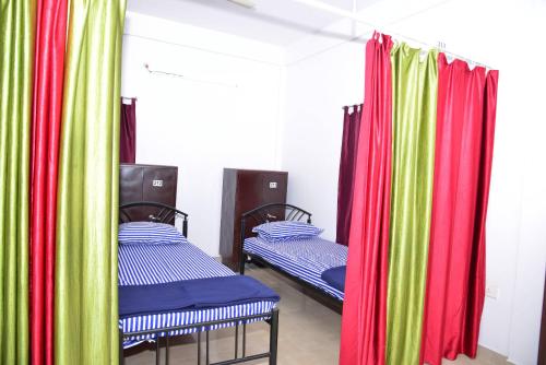 two beds in a room with colorful curtains at Tranquil Hospitality in Bhubaneshwar