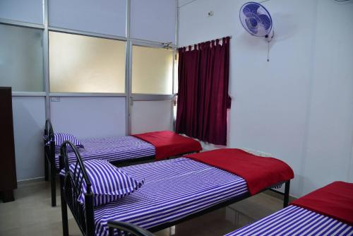 a room with three beds and a window at Tranquil Hospitality in Bhubaneshwar