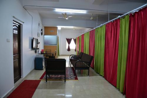a room with red and green curtains and chairs at Tranquil Hospitality in Bhubaneshwar