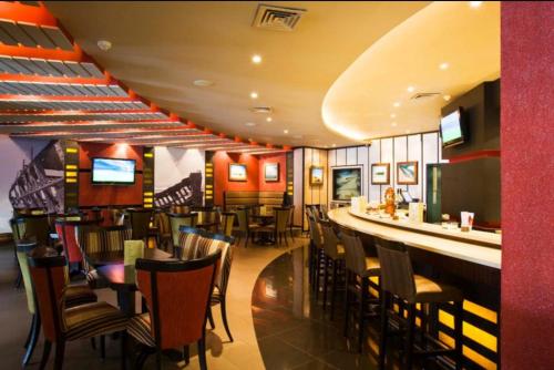 a restaurant with a bar with chairs and tables at Mercure Hotel Windhoek in Windhoek