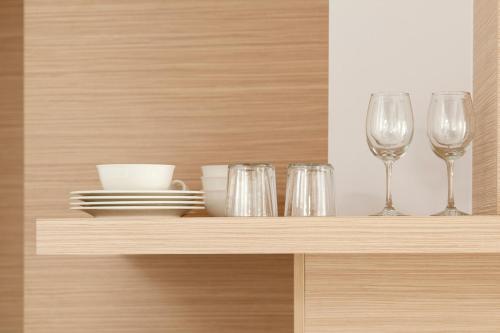 a shelf with glasses and plates and dishes on it at Eric Vökel Boutique Apartments - Hamburg Suites in Hamburg