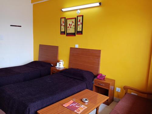a hotel room with two beds and a table at Hotel Shikhar & Restaurant in Almora