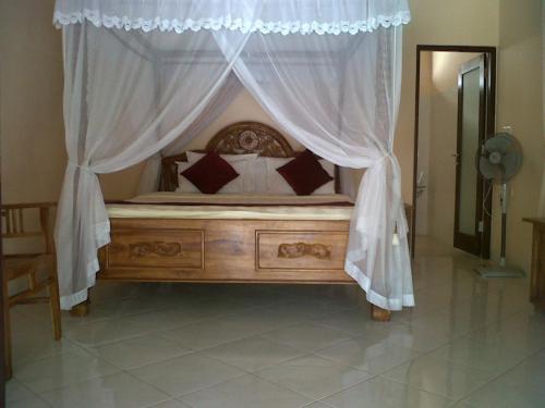 a bedroom with a bed with a canopy and curtains at Mutiara Bali in Candidasa