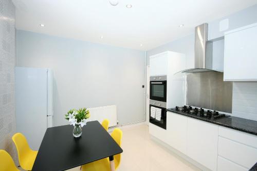 a kitchen with a black table and yellow chairs at Brick Lane Guest House in London