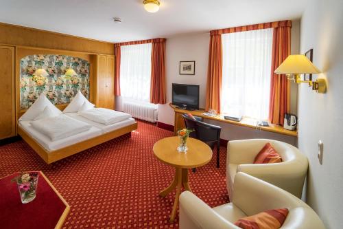 Habitación de hotel con cama, mesa y sillas en Hotel-Gasthof Zum Weyssen Rössle en Schiltach