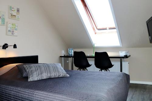 a bedroom with a bed and two black chairs at Taastrup Park Hotel in Tåstrup