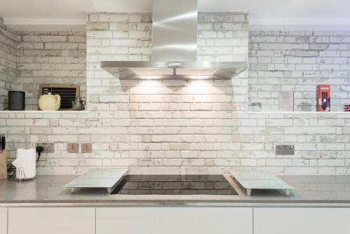 a kitchen with two benches and a white brick wall at Second Nest London Warehouse in London