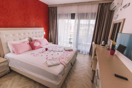 a bedroom with a bed with pink pillows and a television at Miami apartments in Ulcinj