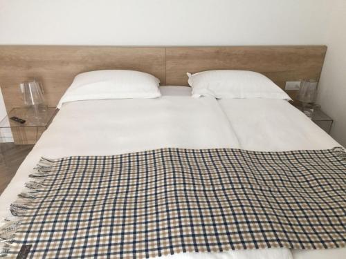 a bed with two pillows and a plaid blanket on it at Hotel Garnì Villa Maria in Riva del Garda
