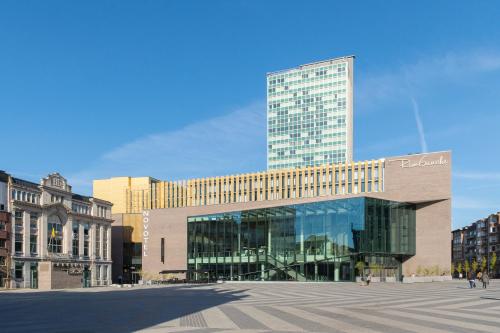 a large glass building with a tall building at Novotel Charleroi Centre in Charleroi