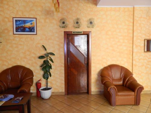 a waiting room with two leather chairs and a door at Hotel Iris in Tîrnăveni