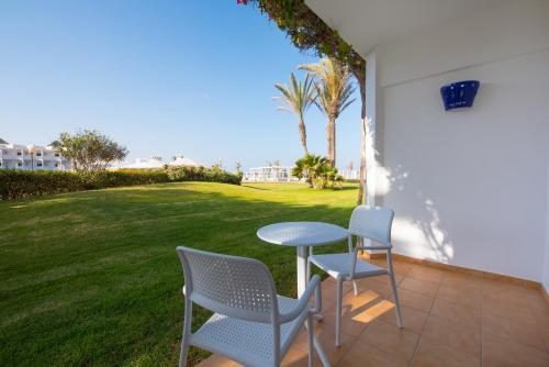 a patio with two chairs and a table and a lawn at Iberostar Waves Founty Beach All Inclusive in Agadir