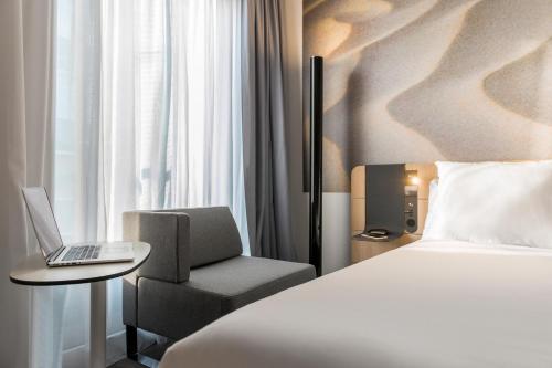 a hotel room with a bed and a chair and a laptop at Novotel Charleroi Centre in Charleroi