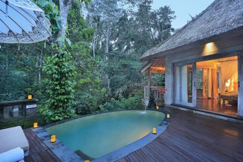 a swimming pool on a deck next to a house at The Kayon Resort in Ubud
