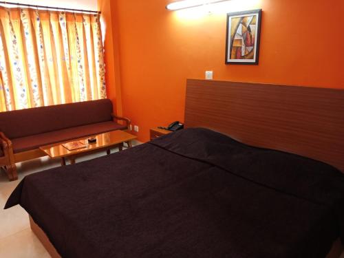 a bedroom with orange walls and a bed and a couch at Hotel Shikhar & Restaurant in Almora