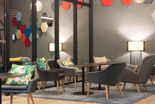 a waiting room with tables and chairs and mirrors at Novotel Charleroi Centre in Charleroi