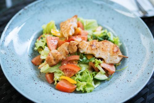 a plate of salad with chicken and lettuce and tomatoes at Hotel Bristol in Banská Štiavnica