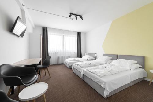 a hotel room with two beds and a table and chairs at Hotel Chesscom in Budapest
