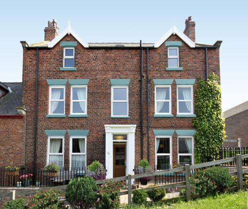 a brick house with a fence in front of it at The Mainstay Luxury Boutique Rooms with Private Parking in Whitby