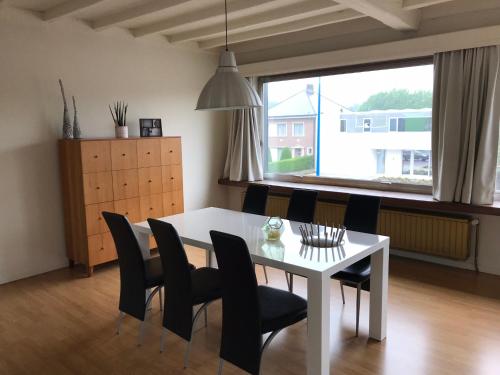a dining room with a white table and black chairs at Appartement224 in Grimbergen