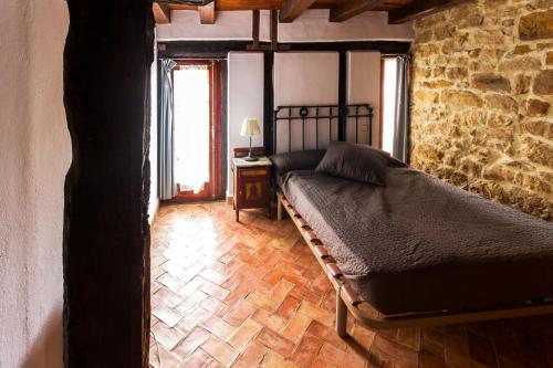 a bedroom with a bed and a stone wall at Casas Canduela in Canduela
