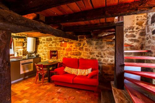 a living room with a red couch and a kitchen at Casas Canduela in Canduela