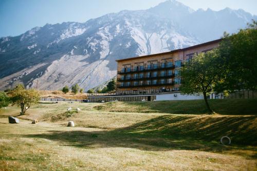 
a large building with a mountain in the distance at Rooms Hotel Kazbegi in Stepantsminda
