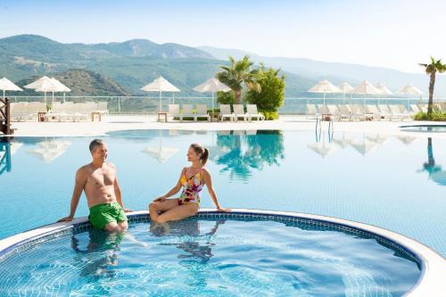 a man and a woman sitting in a swimming pool at Wyndham Residences, Kusadasi Golf & Spa in Kuşadası