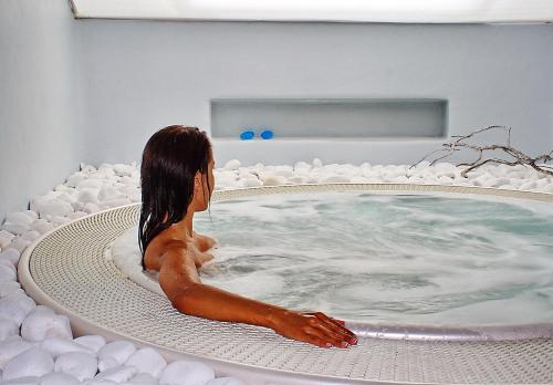 a woman sitting in a jacuzzi tub at Yades - All Sea VIew Suites - Adults only in Naousa