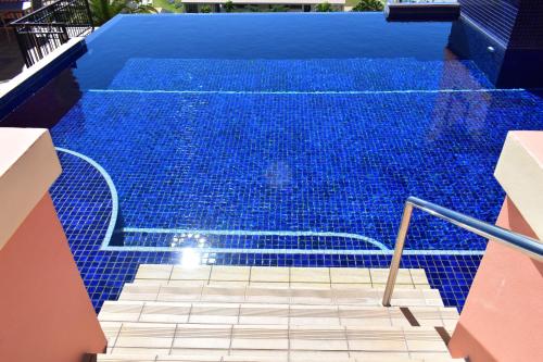 a swimming pool with blue tiles on the floor and stairs at Martinique Whitsunday Resort in Airlie Beach
