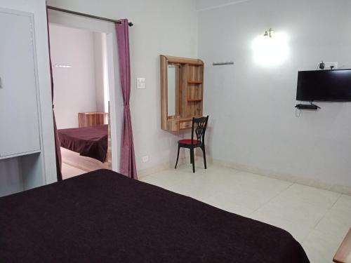 a room with a bed and a chair and a television at Hotel Shikhar & Restaurant in Almora