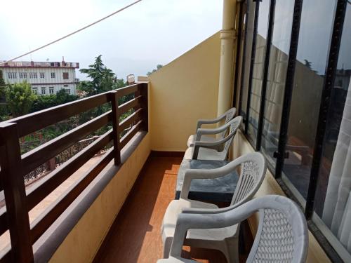 two white chairs sitting on a balcony with a view at Hotel Shikhar & Restaurant in Almora