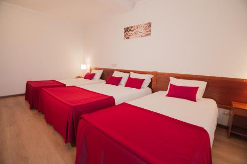 two beds in a room with red and white sheets at Hotel Cristo Rei - Fatima in Fátima