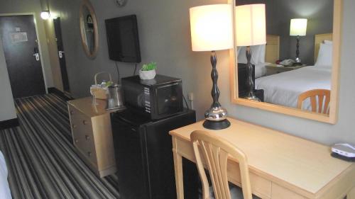 a hotel room with a desk and a bed and a mirror at Travelodge by Wyndham Memphis Airport/Graceland in Memphis