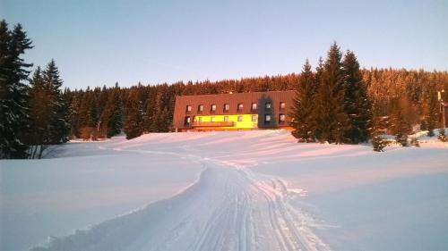 a building in a snow covered field with trees at Pension Horske Zatisi in Horni Misecky