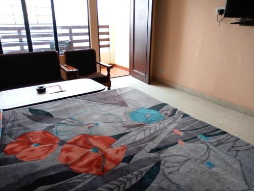 a room with a table and a rug with flowers on it at Hotel Shikhar & Restaurant in Almora