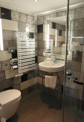 a bathroom with a sink and a toilet and a mirror at Pension Antik in Bad Lobenstein