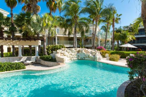 a swimming pool with palm trees and a resort at The Sands at Grace Bay in Grace Bay