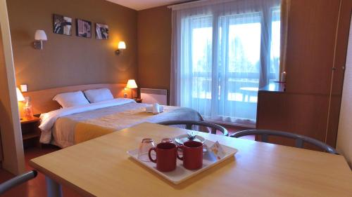 a hotel room with a bed and a table with mugs on it at VVF Haute-Loire Les Estables in Les Estables